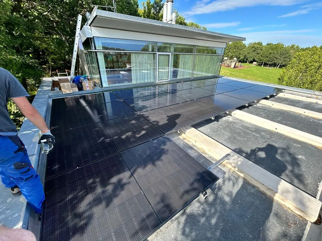 Monteur trägt ein PV-Modul über ein Flachdach in Wien