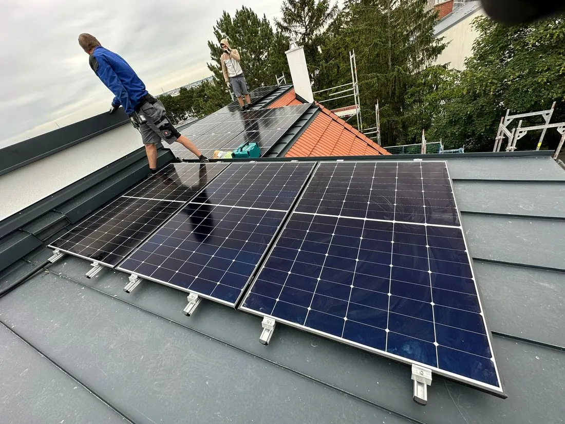Zwei Monteure montieren PV-Module auf einem Schrägdach in Niederösterreich